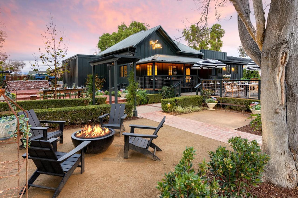 black painted ranch-style boutique Solvang hotel with outdoor firepit and chairs with a sunset sky
